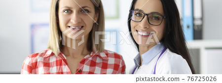 Smiling doctor and patient stand in clinic office Smiling doctor and patient stand in clinic office 76725026