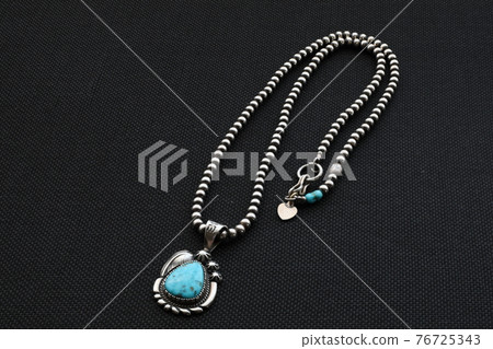 Turquoise silver pendant glows on a black background 76725343