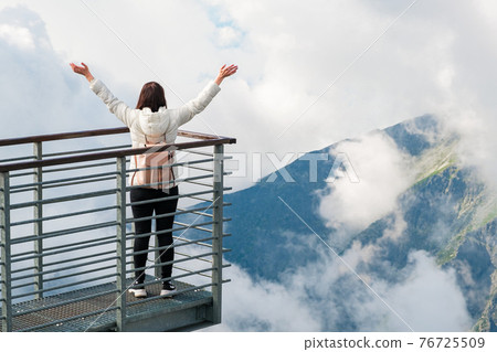 Tourist enjoying of amazing view of mountains and clouds. View from Lomnicky peak in Slovakia. Sport, hiking and active life concept. Tourist enjoying of amazing view of mountains and clouds. View from Lomnicky peak in Slovakia. Sport, hiking and active life concept. 76725509