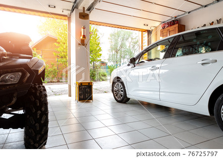 Home suburban countryside modern car and ATV double garage interior with wooden shelf, tools and equipment stuff storage warehouse indoors against sun light. Vehicle parked house parking background 76725797