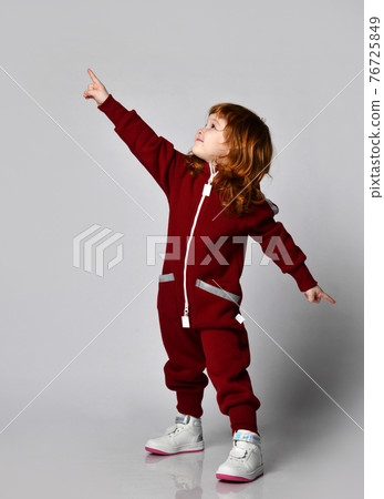 Joyful little red-haired toddler girl in warm 76725849