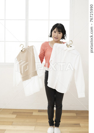 A young woman wondering which clothes to wear A young woman wondering which clothes to wear 76725990