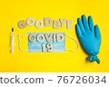 Words GOODBYE COVID 19 from wooden letters and syringe, inflated medical glove and facemask. vaccine and the end of epidemic concept. 76726034