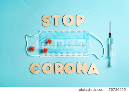 Words STOP CORONA from wooden letters, syringe and facemask. Vaccination and the end of epidemic concept. 76726035
