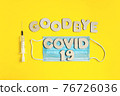 Words GOODBYE COVID 19 from wooden letters, syringe and facemask. Vaccination and the end of epidemic concept. 76726036