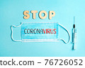 Words STOP CORONAVIRUS from wooden letters and letters on facemask and syringe. Vaccination and the end of epidemic concept. 76726052