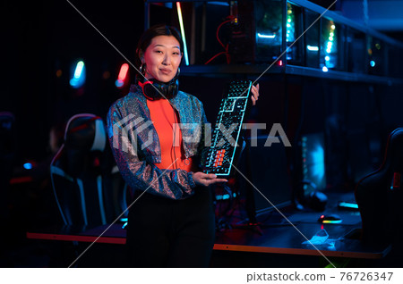 An experienced esports girl advertises a new gaming keyboard in the neon light 76726347