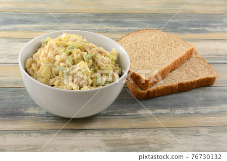 Albacore tuna salad with chopped apple and avocado in white bowl next to two whole wheat bead slices Albacore tuna salad with chopped apple and avocado in white bowl next to two whole wheat bead slices 76730132