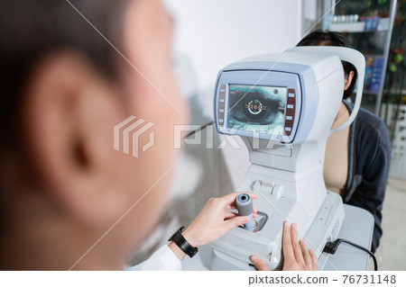 a male ophthalmologist is operating an eye computer for a female patient to examine the patient's eyes a male ophthalmologist is operating an eye computer for a female patient to examine the patient's eyes 76731148