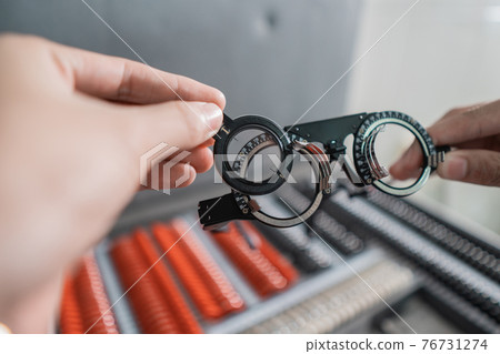 a doctor's hand is holding the experimental lens frame in a room a doctor's hand is holding the experimental lens frame in a room 76731274