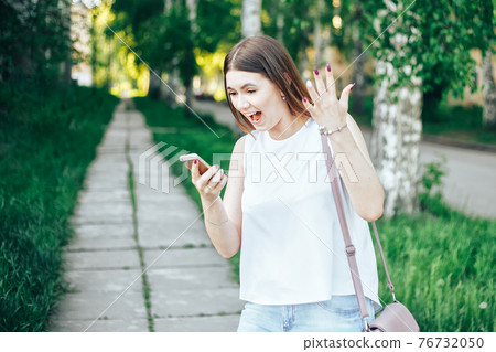 girl shouts on mobile phone in park 76732050