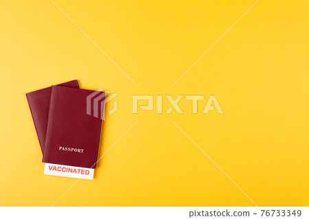 Passports with vaccinated stamp on blank on yellow background Passports with vaccinated stamp on blank on yellow background 76733349