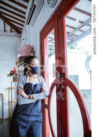 boring woman florist wearing apron and face mask lean on door 76734797