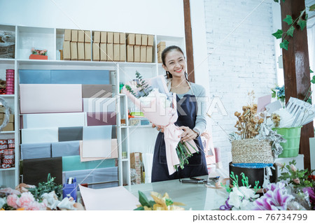 happy young woman florist working in flower shop holding flannel flower happy young woman florist working in flower shop holding flannel flower 76734799