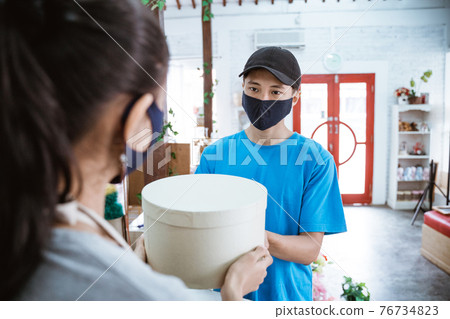 portrait smiling young female shopkeeper receiving a package portrait smiling young female shopkeeper receiving a package 76734823