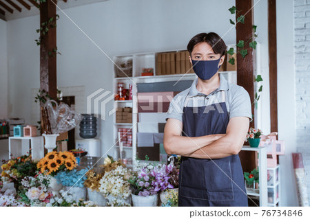man using face mask florist standing crossed arm with fresh flowers in his floral shop man using face mask florist standing crossed arm with fresh flowers in his floral shop 76734846