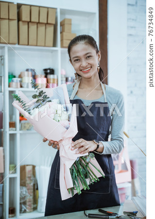 happy young woman florist working in flower shop holding flannel flower happy young woman florist working in flower shop holding flannel flower 76734849