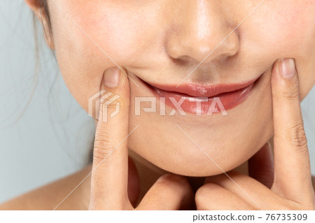 Woman raising the corner of the mouth Woman raising the corner of the mouth 76735309
