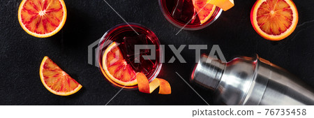 Negroni cocktails panorama with blood oranges on black Negroni cocktails panorama with blood oranges on black 76735458