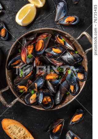 Mussels in a pan, shot from the top with lemon and toasted bread Mussels in a pan, shot from the top with lemon and toasted bread 76735485