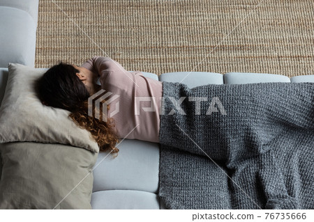 Exhausted latin woman sleep on couch in clothes under plaid Exhausted latin woman sleep on couch in clothes under plaid 76735666