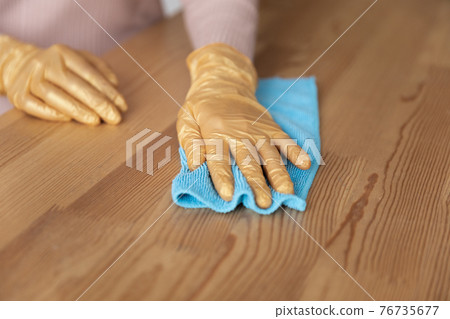 Woman hands in latex gloves rub wooden surface with cloth 76735677