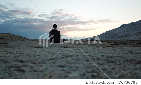 A guy meditates at dawn in the mountains. 76736783