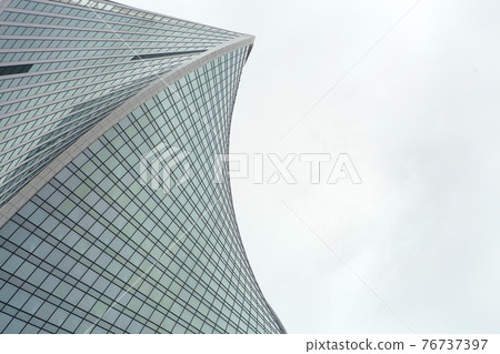 Modern architecture of skyscrapers, office buildings and business centers with unusual geometry. Modern skyscraper against a gray sky in the business district of the city 76737397