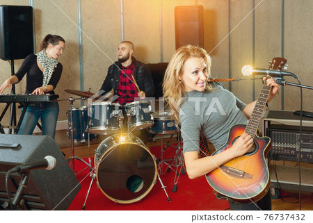 Attractive female soloist playing guitar and singing with her mu Attractive female soloist playing guitar and singing with her mu 76737432