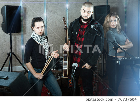 expressive group of rock musicians posing with instruments expressive group of rock musicians posing with instruments 76737604
