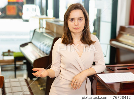 Pretty woman seller in piano music store 76738412