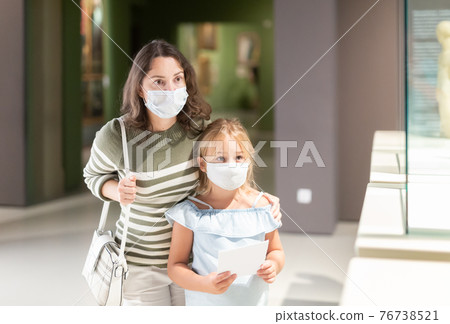 Girl with mother in masks looking with interest at art objects 76738521