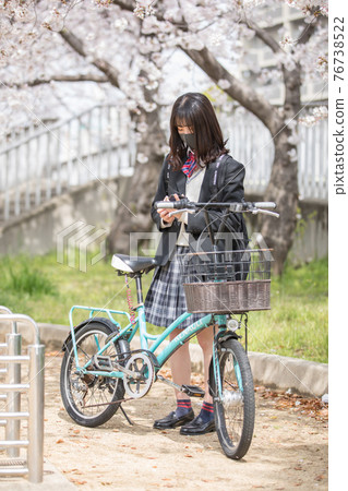 High school girl looking at a smartphone on the way to school High school girl looking at a smartphone on the way to school 76738522