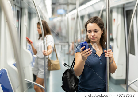 Positive woman reading from mobile phone screen in metro Positive woman reading from mobile phone screen in metro 76738558