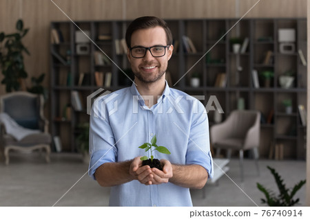 Portrait of smiling businessman hold seedling in hands Portrait of smiling businessman hold seedling in hands 76740914
