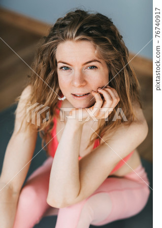 Portrait of a smiling girl in sports clothes, resting after a workout. Recreation, leisure, sports, yoga. Portrait of a smiling girl in sports clothes, resting after a workout. Recreation, leisure, sports, yoga. 76740917