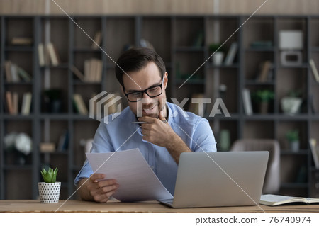 Smiling male employee read good news in paper contract 76740974