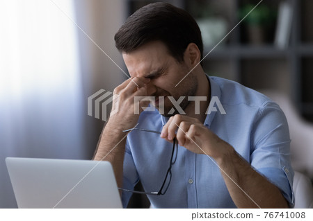 Exhausted man suffer from headache working on laptop Exhausted man suffer from headache working on laptop 76741008
