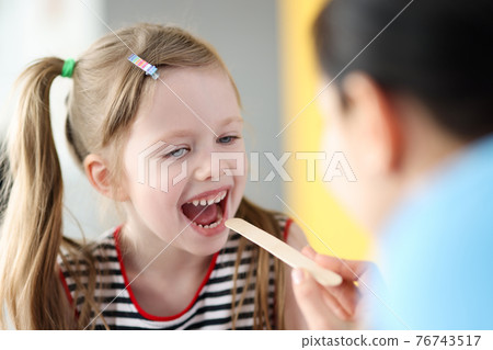 Pediatrician doctor examining throat of little girl with spatula Pediatrician doctor examining throat of little girl with spatula 76743517