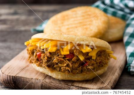 Arepa with shredded beef and cheese on wooden background. 76745452