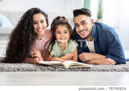 Family Pastimes And Activities. Happy Arabic Parents Reading Book With Little Daughter Family Pastimes And Activities. Happy Arabic Parents Reading Book With Little Daughter 76748824
