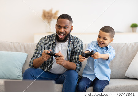 Excited African Daddy And Son Boy Playing Game At Home 76748841
