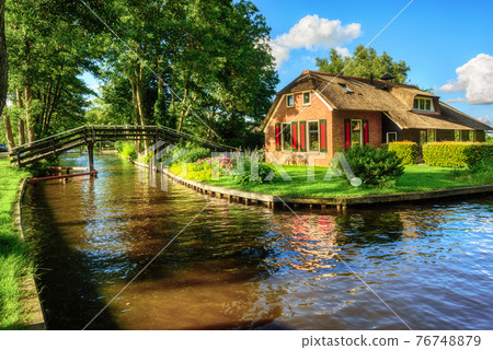 Water canal in Giethoorn village, Netherlands 76748879