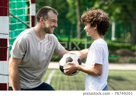 Sportive adult dad playing soccer with his son Sportive adult dad playing soccer with his son 76749201