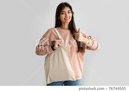 Woman standing with blank canvas tote bag showing thumb up 76749505
