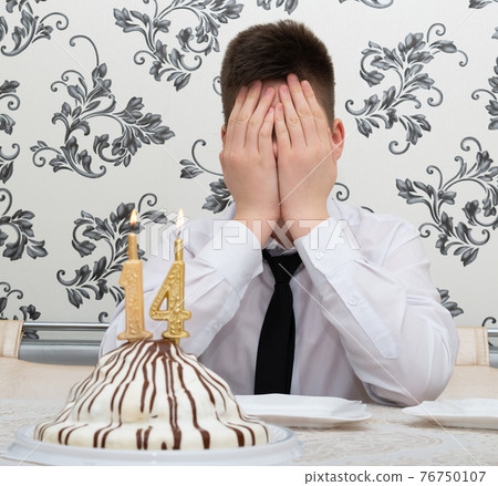 teen boy at table with cake for his fourteenth birthday teen boy at table with cake for his fourteenth birthday 76750107