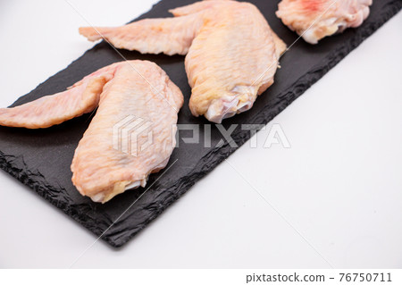 Chicken wings lined up in a black square tray Chicken wings lined up in a black square tray 76750711
