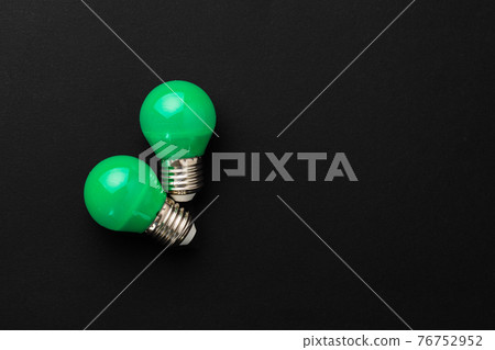 Two green light bulbs on black background 76752952