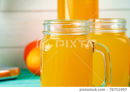 Glass with orange juice on green wooden table Glass with orange juice on green wooden table 76752997