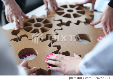 Group of business people stacking wooden gears closeup 76754224